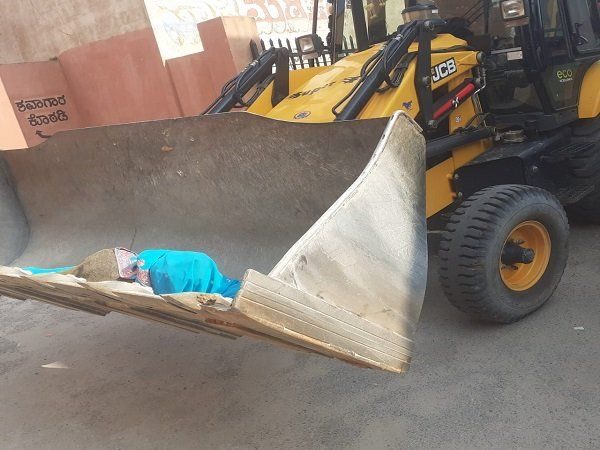 రోడ్డుపై కుప్ప‌కూలిన మ‌హిళ : జేసీబీలో ద‌వాఖాన‌కు..