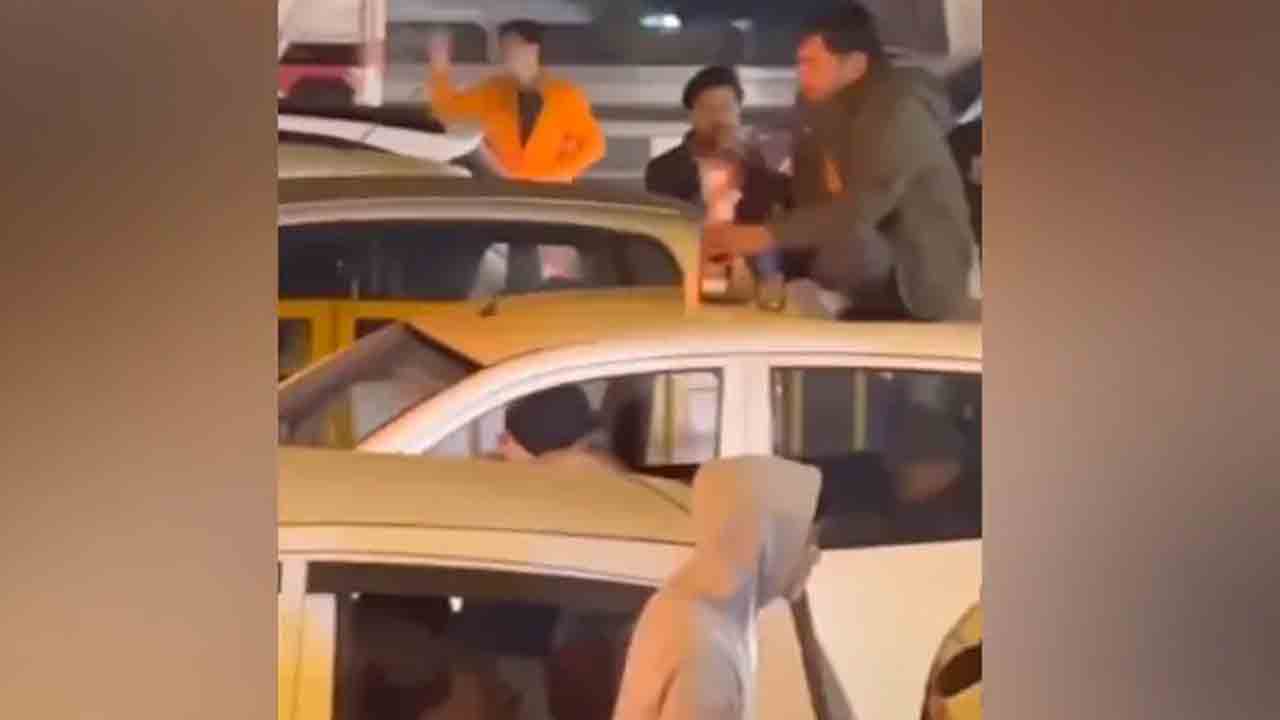 వీడెవడండి బాబు.. నడి రోడ్డులో కారు టాప్‌పై కూర్చుని మందు తాగతూ..