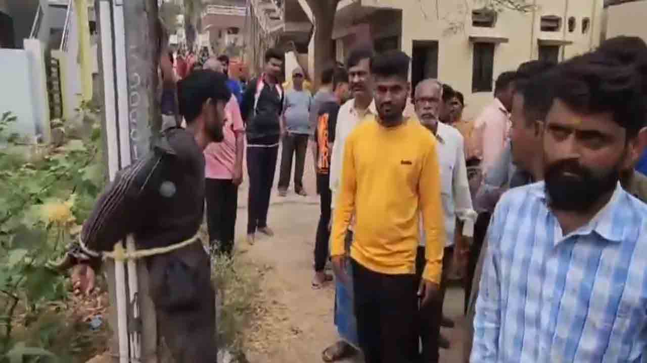 Man Thrashed By Locals | మహిళ స్నానం చేస్తుండగా వీడియో రికార్డ్‌ చేసిన వ్యక్తి.. స్తంభానికి కట్టేసి కొట్టిన   జనం