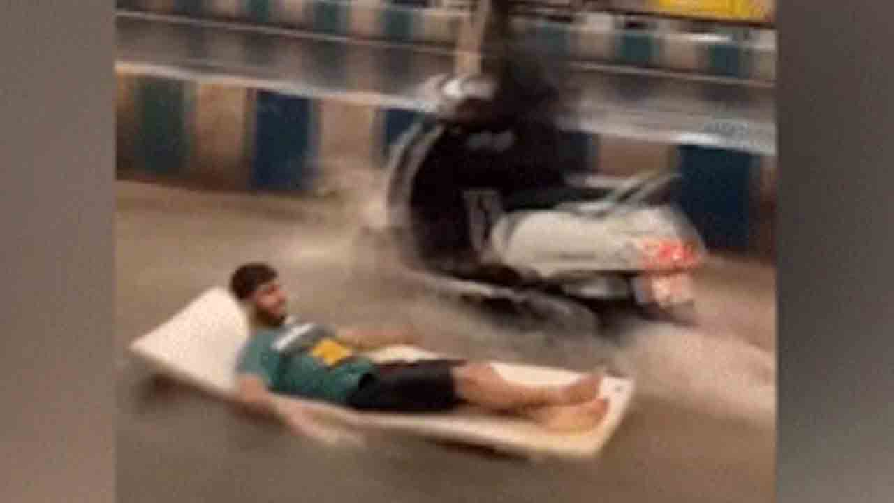 Watch: వర్షం తర్వాత రోడ్డుపైనున్న నీటిలో పరుపుపై తేలియాడిన వ్యక్తి.. వీడియో వైరల్‌