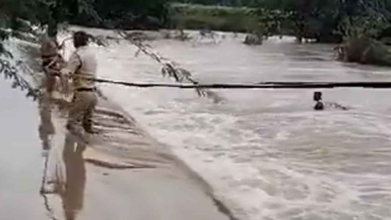 Heavy rains | వరద నీటిలో కొట్టుకుపోతున్న వ్యక్తిని కాపాడిన పోలీసులు : వీడియో