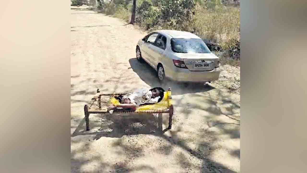 రోడ్డుపై మంచం వేసి ఇసుక లారీల అడ్డగింత