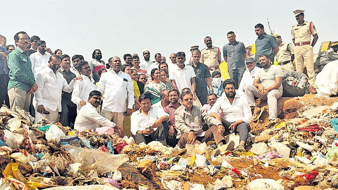 చెత్తలో కూర్చొని.. నిరసన తెలిపి..