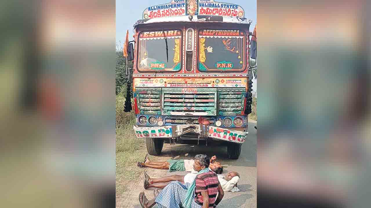 ధాన్యాన్ని ఎందుకు తరలించరు.. రోడ్డుపై వెళ్లే లారీకి అడ్డంగా పడుకొని రైతుల నిరసన