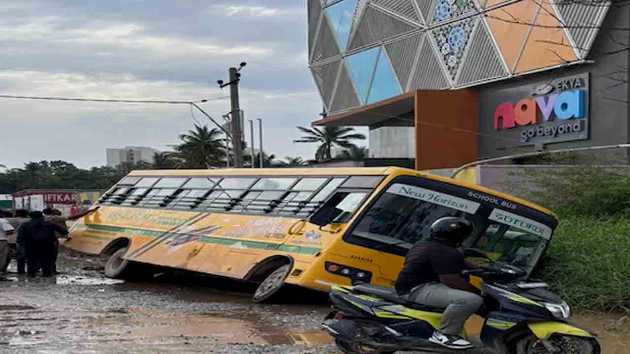 School Bus Topples | బెంగళూరులో అద్వాన్నంగా రోడ్లు.. గుంతలోకి ఒరిగిపోయిన బస్సు
