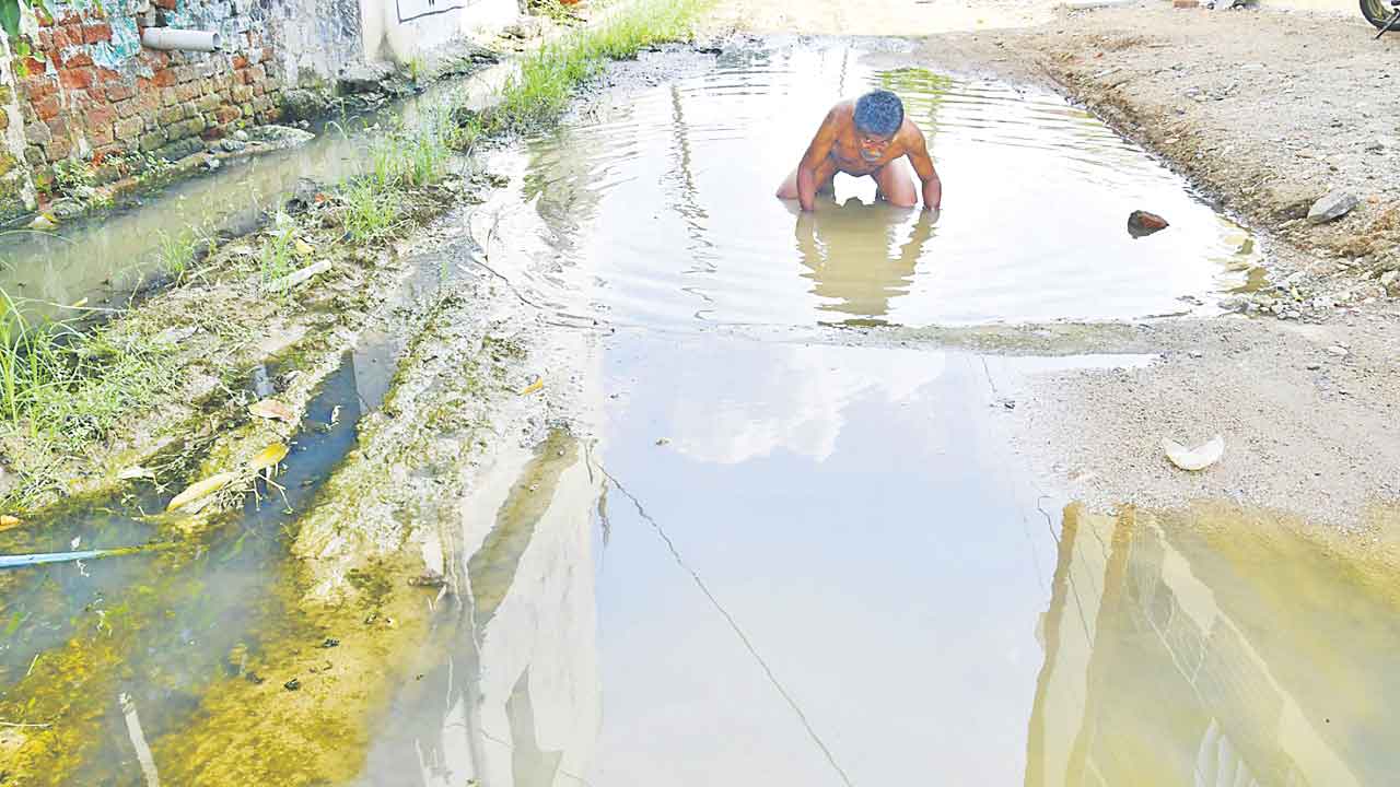 మురుగు నీటిలో కూర్చుని నిరసన