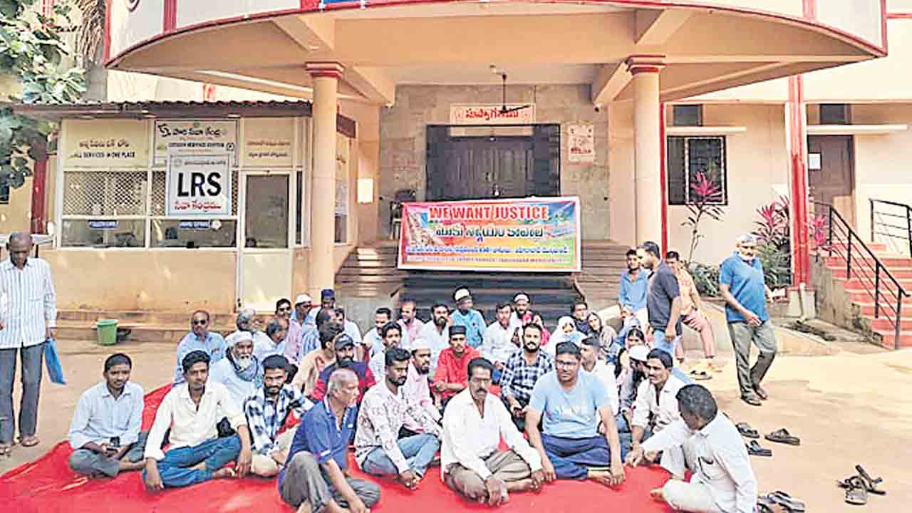 ఇండ్ల స్థలాలు కాపాడండి.. ఆఫీస్‌ ఎదుట బైఠాయించి ధర్నా చేసిన బాధితులు